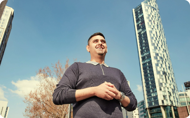 man smiling and standing in front of building